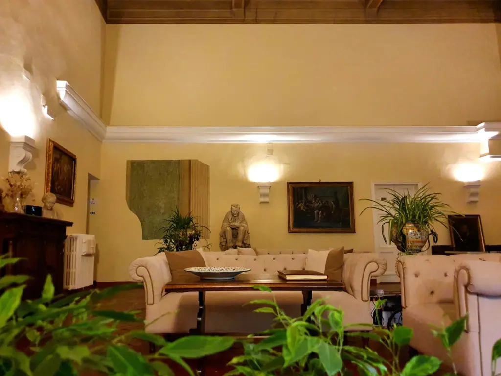 High-ceilinged salon with sofas, plants and paintings