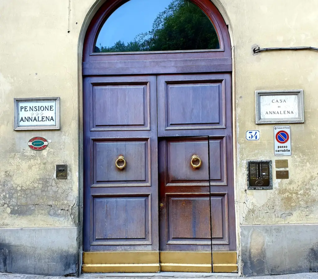 Arched wooden entrance door with the Pensione Annalena and Casa di Annalena plaques