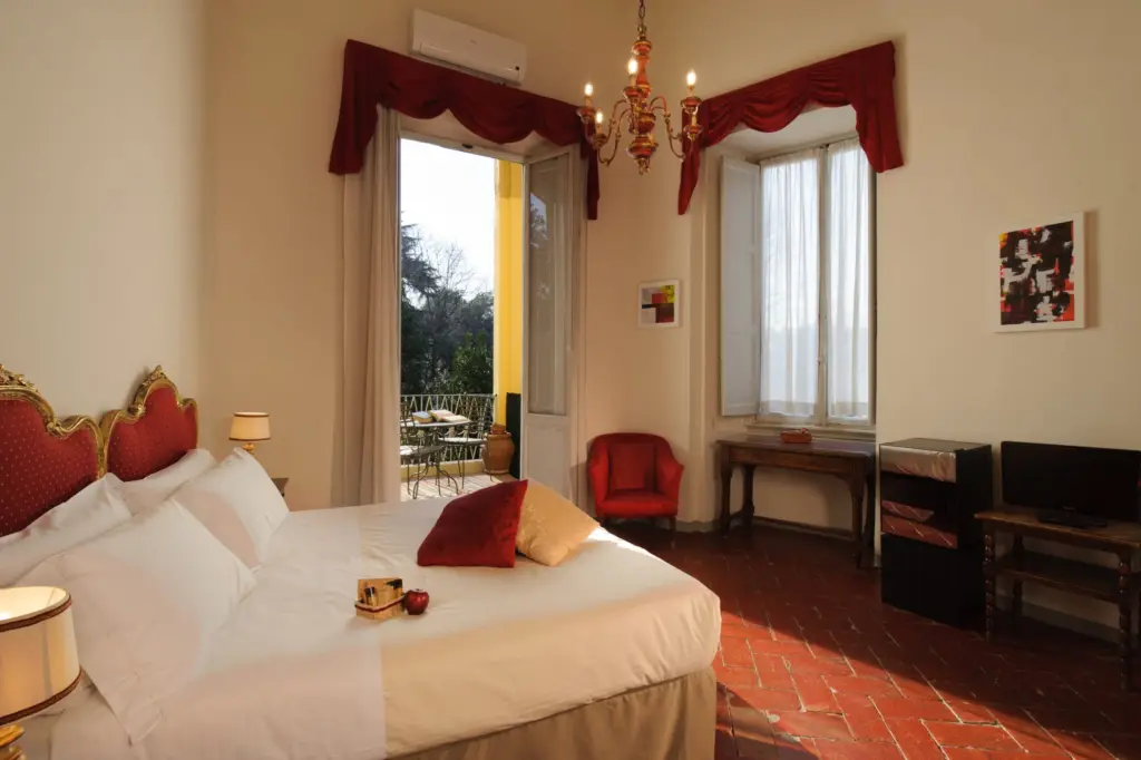 Double room with red curtains, a chandelier and a balcony door