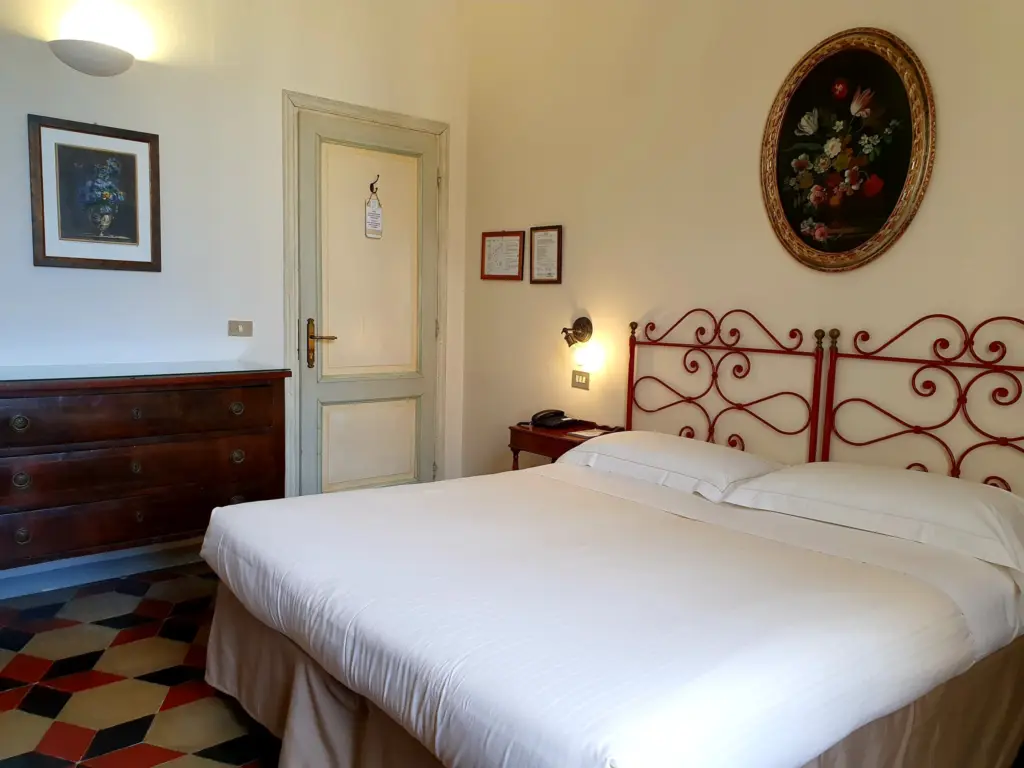 Double room with a red iron bed and a painting with a gilded frame