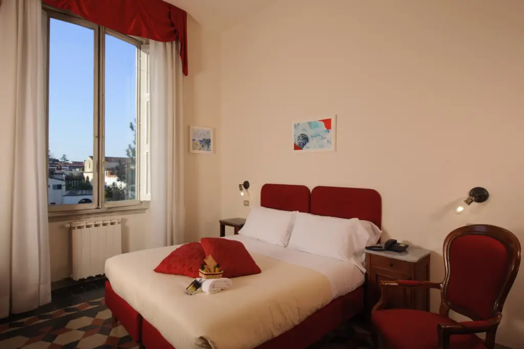 Double room with red bedspread and a window over the rooftops