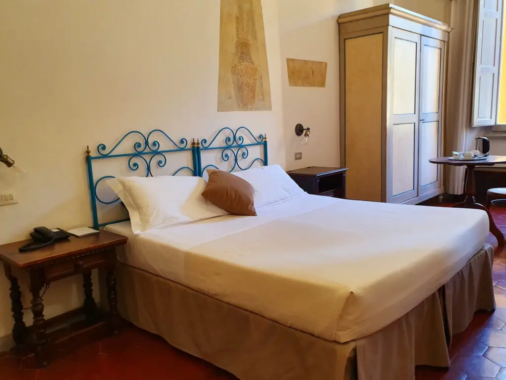 Double room with a blue wrought-iron bed and antique furniture