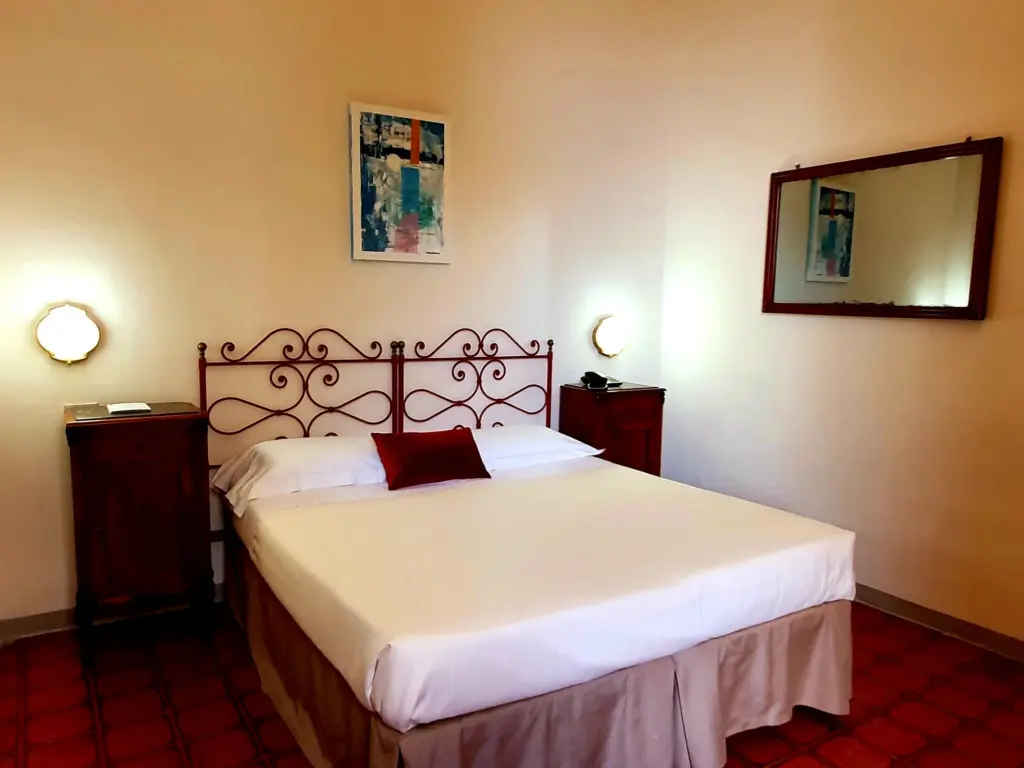 Double room with a red iron bed and a large mirror