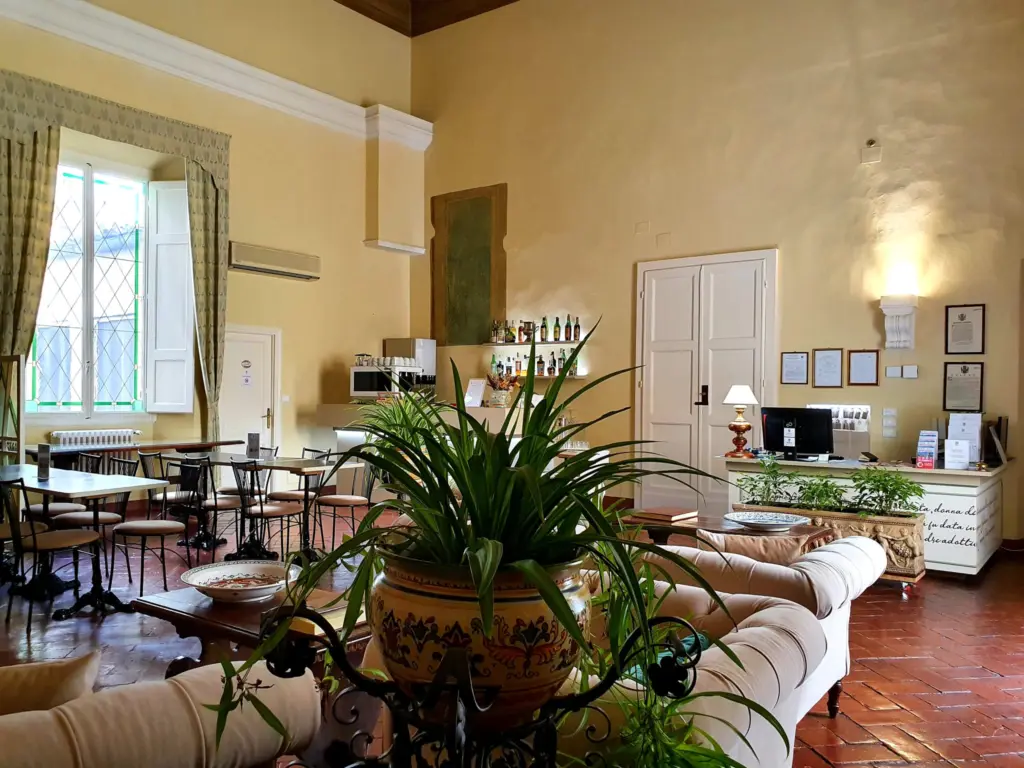 Salon with armchairs and plants, and the reception desk in the background