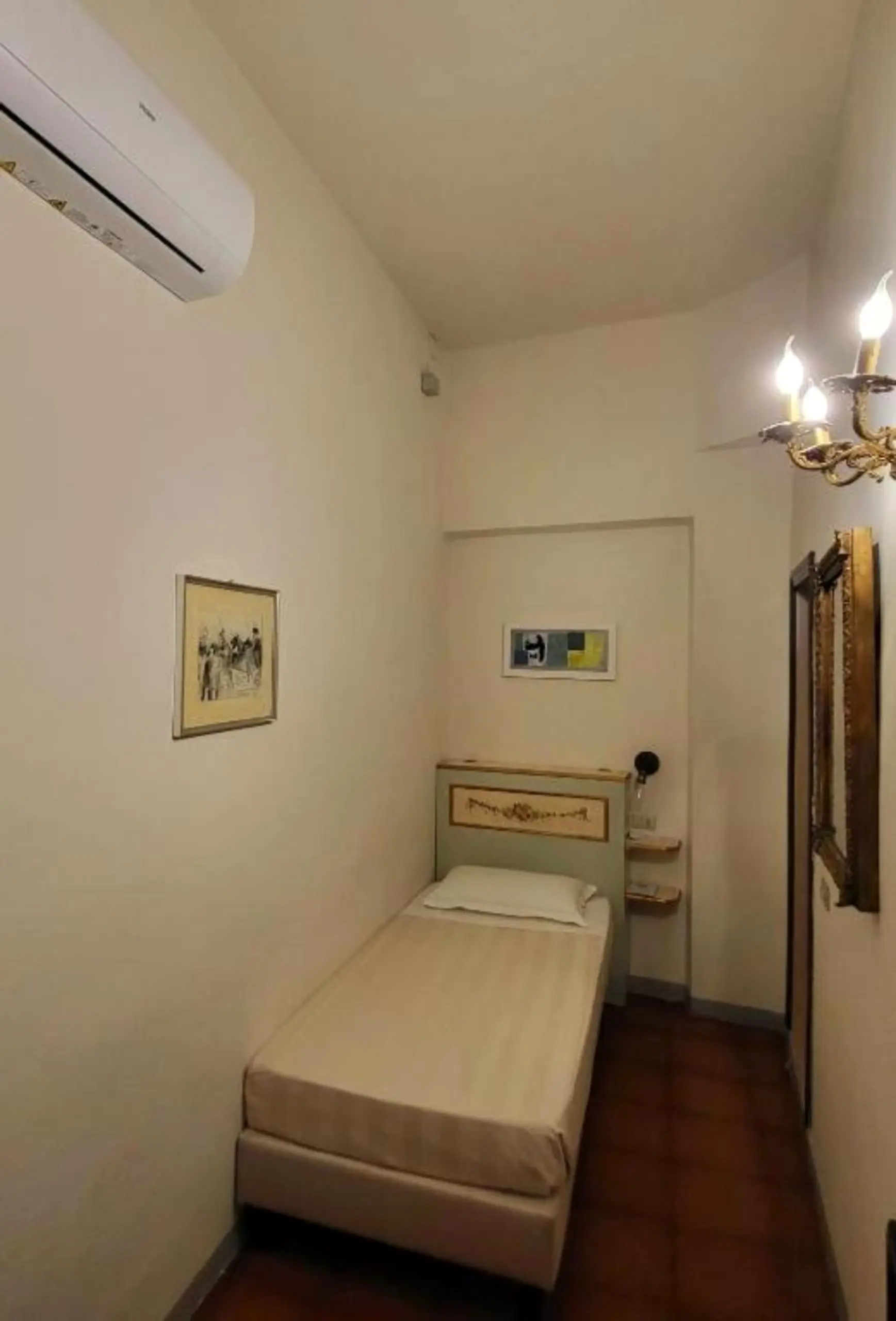 Camera singola con letto singolo, climatizzatore a parete e stampa incorniciata