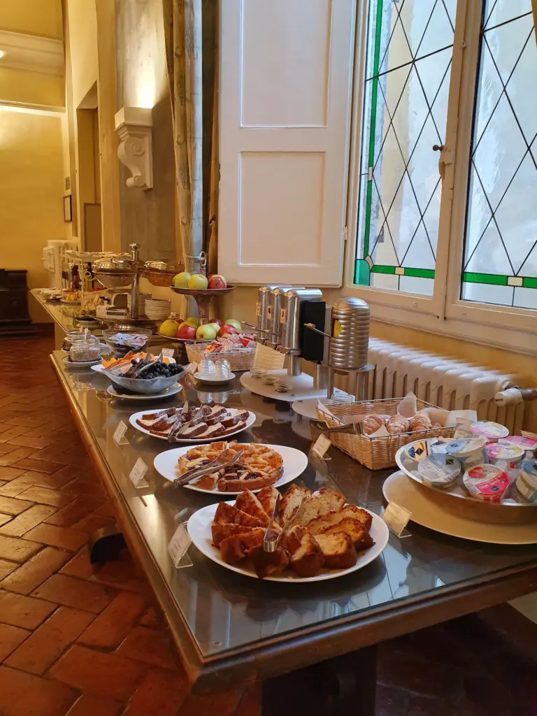 Torte, crostate, cornetti, frutta e yogurt sul buffet accanto a una finestra a vetri piombati